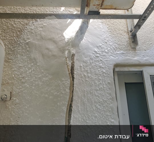 חומר איטום לבן סביב צינור על קיר חיצוני